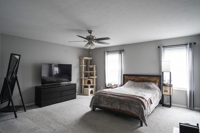 bedroom with light colored carpet, a ceiling fan, baseboards, and a textured ceiling