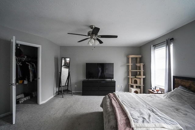 bedroom featuring carpet, a walk in closet, baseboards, a ceiling fan, and a closet