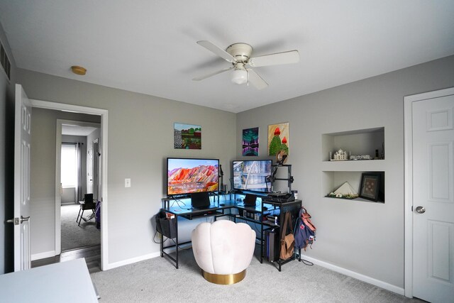 carpeted office space with a ceiling fan and baseboards