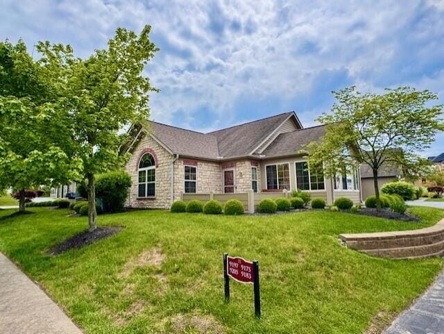 view of front of property with a front yard and stone siding