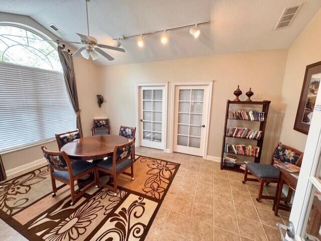 dining room with rail lighting, light tile patterned floors, ceiling fan, vaulted ceiling, and baseboards