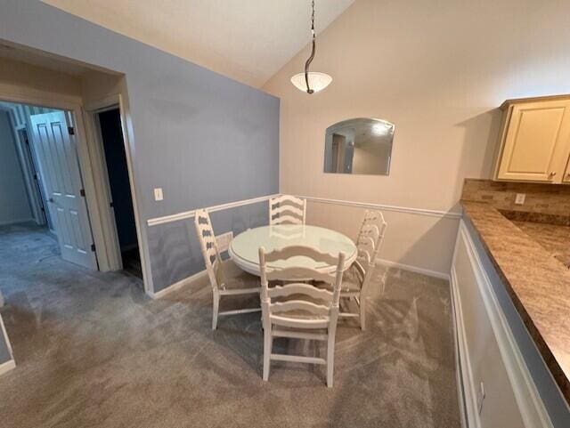 dining room featuring dark colored carpet, baseboards, and high vaulted ceiling