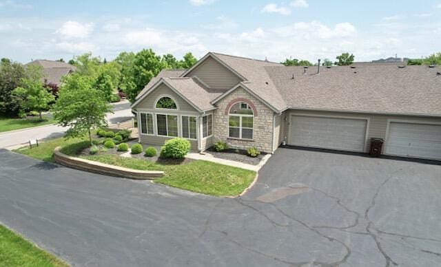ranch-style home featuring asphalt driveway, stone siding, a garage, and a shingled roof
