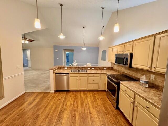 kitchen featuring stainless steel appliances, a peninsula, high vaulted ceiling, decorative light fixtures, and light wood-style flooring