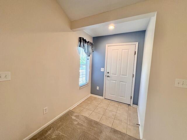 entrance foyer with light tile patterned floors, baseboards, and light colored carpet