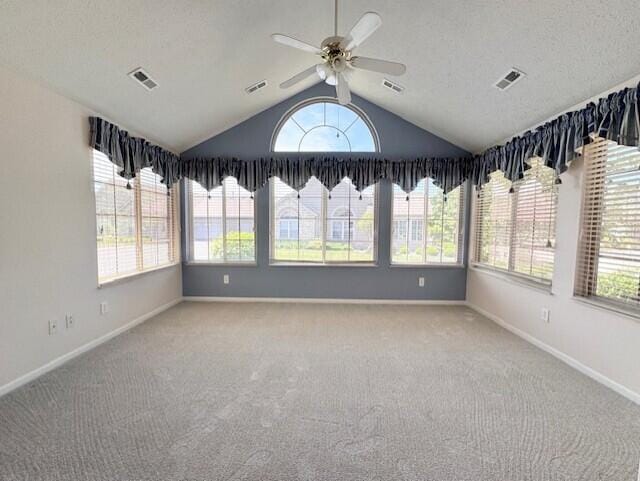 unfurnished sunroom with plenty of natural light, lofted ceiling, carpet flooring, and baseboards