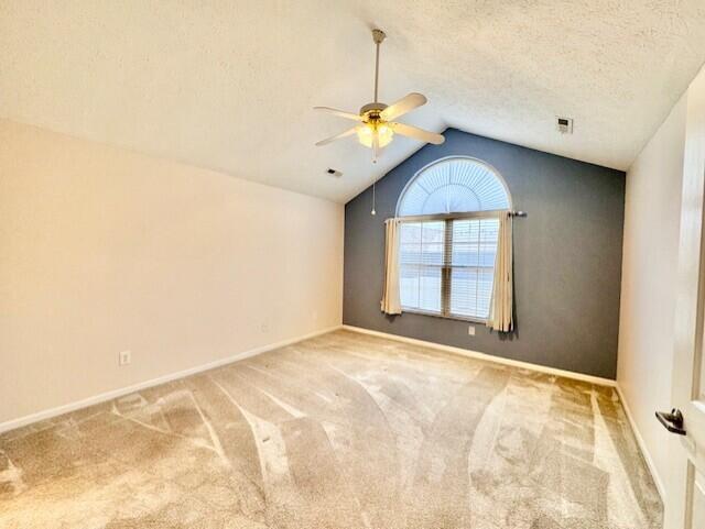 unfurnished room featuring a ceiling fan, vaulted ceiling, carpet flooring, baseboards, and a textured ceiling