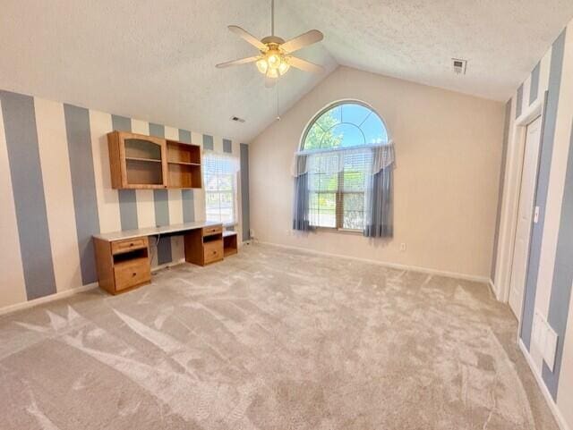 unfurnished bedroom featuring light carpet, vaulted ceiling, baseboards, a textured ceiling, and a ceiling fan