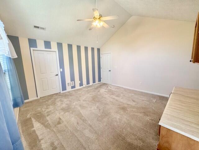 unfurnished bedroom with lofted ceiling, carpet flooring, a ceiling fan, and baseboards