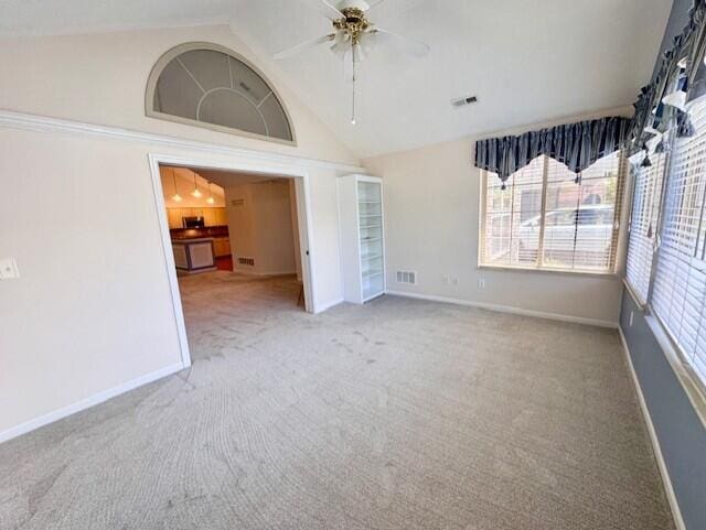 unfurnished room with a ceiling fan, carpet flooring, baseboards, and high vaulted ceiling
