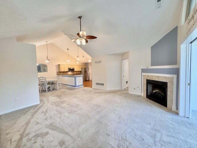 unfurnished living room featuring lofted ceiling, ceiling fan, light carpet, baseboards, and a fireplace