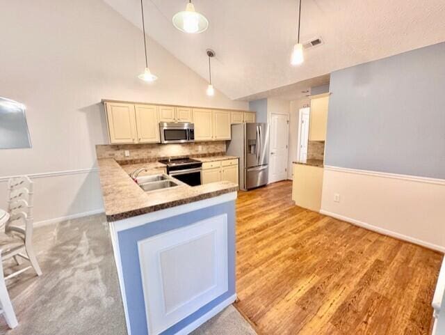 kitchen featuring stainless steel appliances, a sink, cream cabinets, backsplash, and high vaulted ceiling