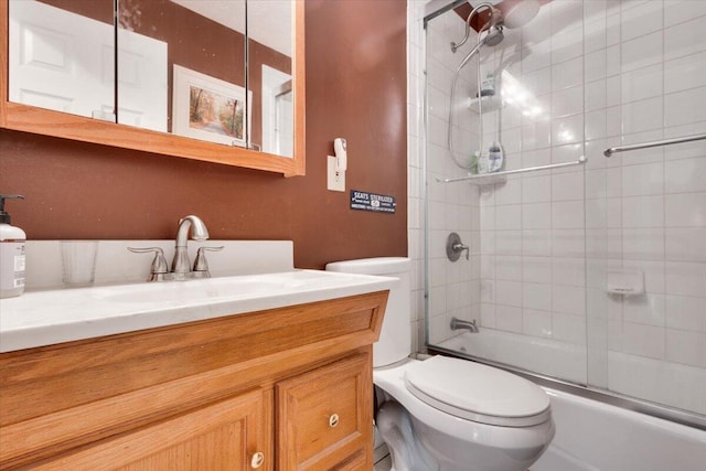 full bath featuring toilet, vanity, and combined bath / shower with glass door