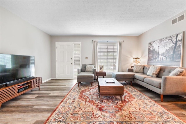 living area with wood finished floors, a textured ceiling, and baseboards