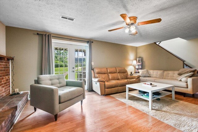 living area with light wood-style flooring, ceiling fan, french doors, and a textured ceiling