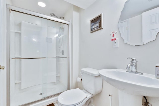 bathroom with toilet, a shower stall, and a sink