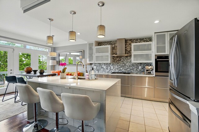 516 Western Ave, Covington, KY 41011 - kitchen featuring appliances with stainless steel finishes, wall chimney exhaust hood, a sink, light countertops, and decorative backsplash