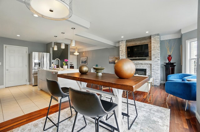 516 Western Ave, Covington, KY 41011 - kitchen with stainless steel fridge with ice dispenser, light wood-type flooring, a fireplace, a sink, and hanging light fixtures