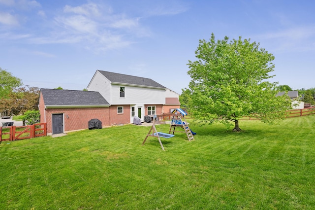 back of property with a playground, brick siding, and a shingled roof