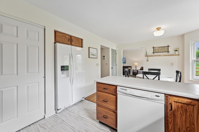kitchen featuring white appliances, brown cabinets, an office area, light wood finished floors, and light countertops