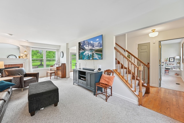 living room with a fireplace, stairway, baseboards, and carpet floors