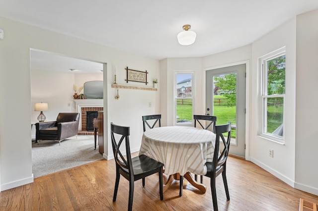 dining space featuring baseboards, a fireplace, and light wood-type flooring