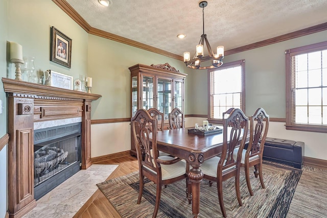 dining space with a chandelier, a textured ceiling, healthy amount of natural light, baseboards, and ornamental molding