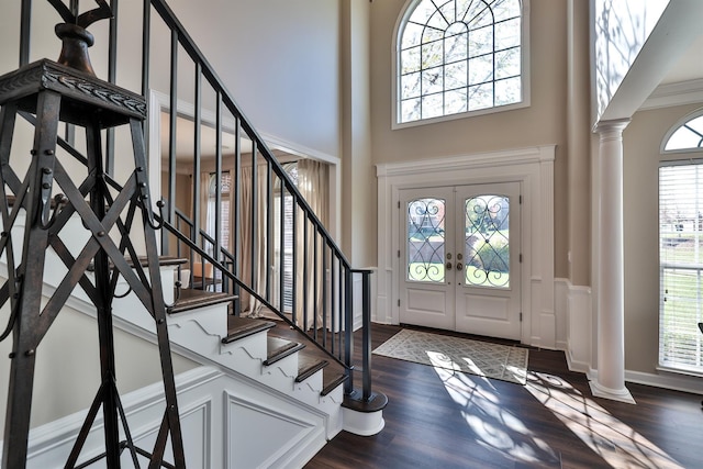 foyer featuring decorative columns, a high ceiling, dark wood-style floors, stairs, and french doors