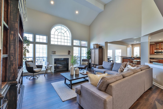 living room with high vaulted ceiling, a high end fireplace, dark wood-style floors, ornate columns, and recessed lighting