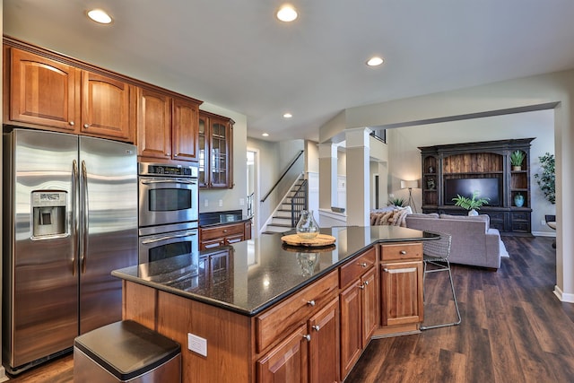 kitchen featuring appliances with stainless steel finishes, dark wood-type flooring, recessed lighting, a center island, and dark stone countertops
