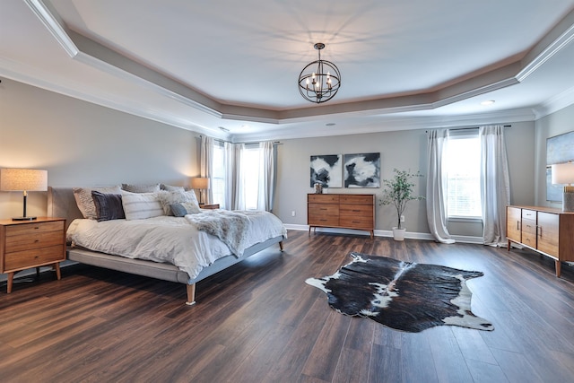 bedroom featuring a tray ceiling, ornamental molding, dark wood-style flooring, a chandelier, and baseboards