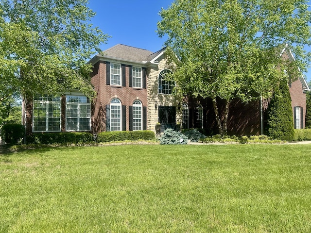 colonial house featuring a front yard and brick siding