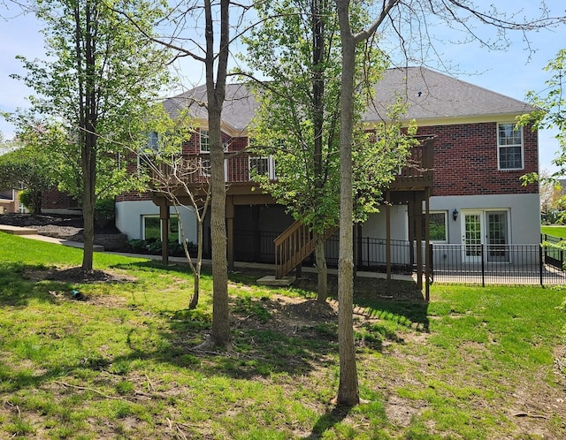 back of house with brick siding, a wooden deck, a shingled roof, and french doors