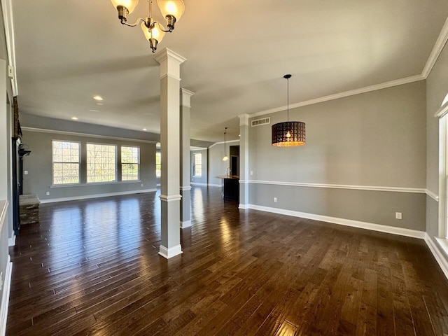 unfurnished dining area with decorative columns, a chandelier, crown molding, dark wood-style flooring, and baseboards