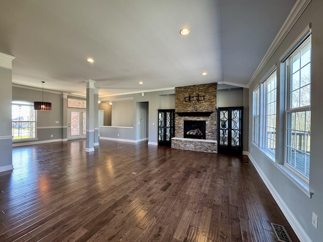 unfurnished living room featuring ornamental molding, ornate columns, dark wood-type flooring, baseboards, and a fireplace