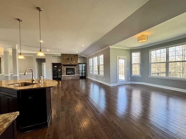 kitchen with a sink, open floor plan, crown molding, baseboards, and dark wood-style flooring