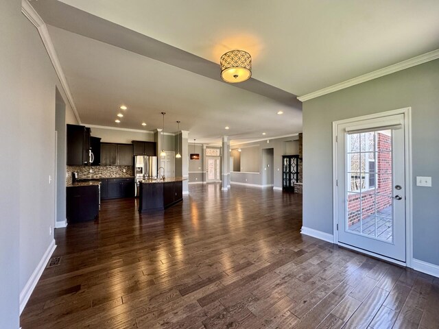 unfurnished living room with ornamental molding, dark wood-style floors, baseboards, and recessed lighting