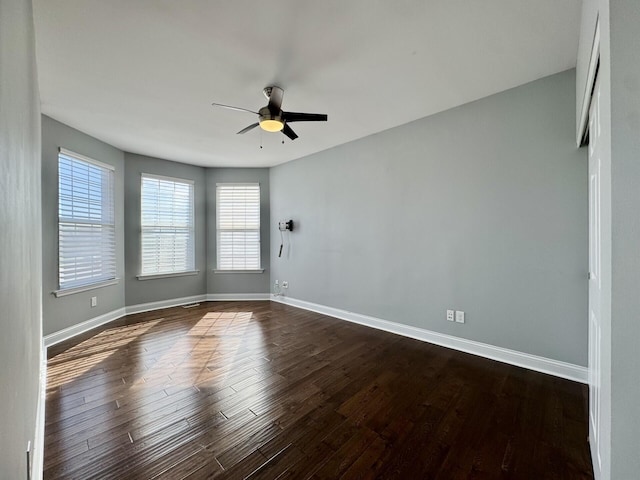 unfurnished room with ceiling fan, healthy amount of natural light, baseboards, and dark wood-style flooring