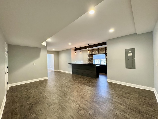unfurnished living room with electric panel, baseboards, recessed lighting, and dark wood finished floors