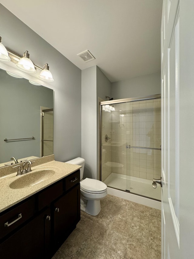 bathroom featuring a stall shower, toilet, vanity, and tile patterned flooring
