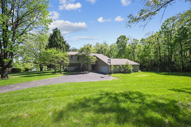 view of grassy yard with driveway and a garage