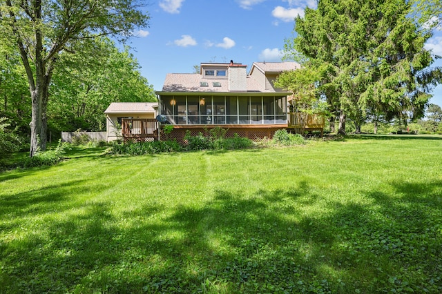 rear view of house featuring a sunroom, a lawn, and a wooden deck