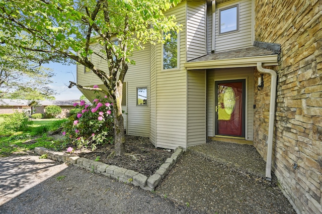 view of exterior entry with a shingled roof