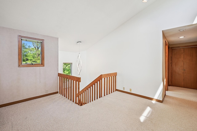 hall with an upstairs landing, carpet, baseboards, and lofted ceiling