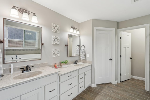 574 Ravensridge Ct, Alexandria, KY 41001 - full bathroom with double vanity, wood finished floors, baseboards, and a tub to relax in