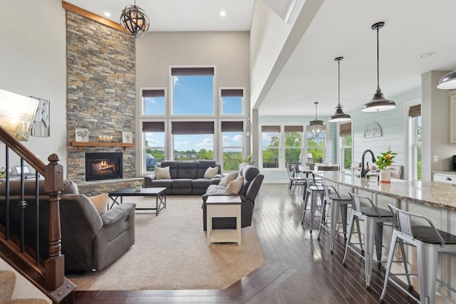 574 Ravensridge Ct, Alexandria, KY 41001 - living area with a stone fireplace, dark wood finished floors, a high ceiling, a chandelier, and recessed lighting