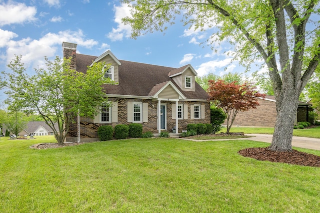 cape cod-style house featuring brick siding, a front yard, a chimney, and roof with shingles