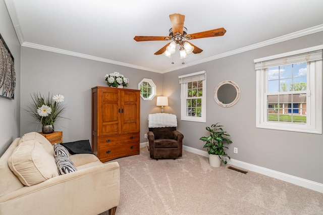 sitting room with carpet, baseboards, ornamental molding, and a ceiling fan