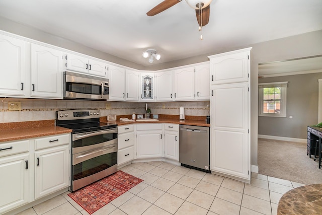 kitchen featuring stainless steel appliances, light tile patterned floors, white cabinets, and ornamental molding