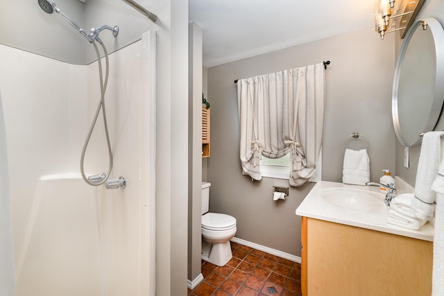 bathroom with a shower, vanity, baseboards, and toilet